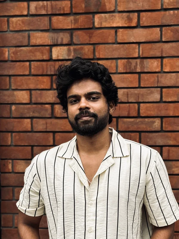 Rahul M standing in front of a brick wall